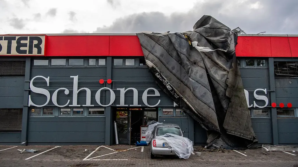 Teile-eines-Dachs-haengen-ueber-die-Fassade-eines-Innenausstatters