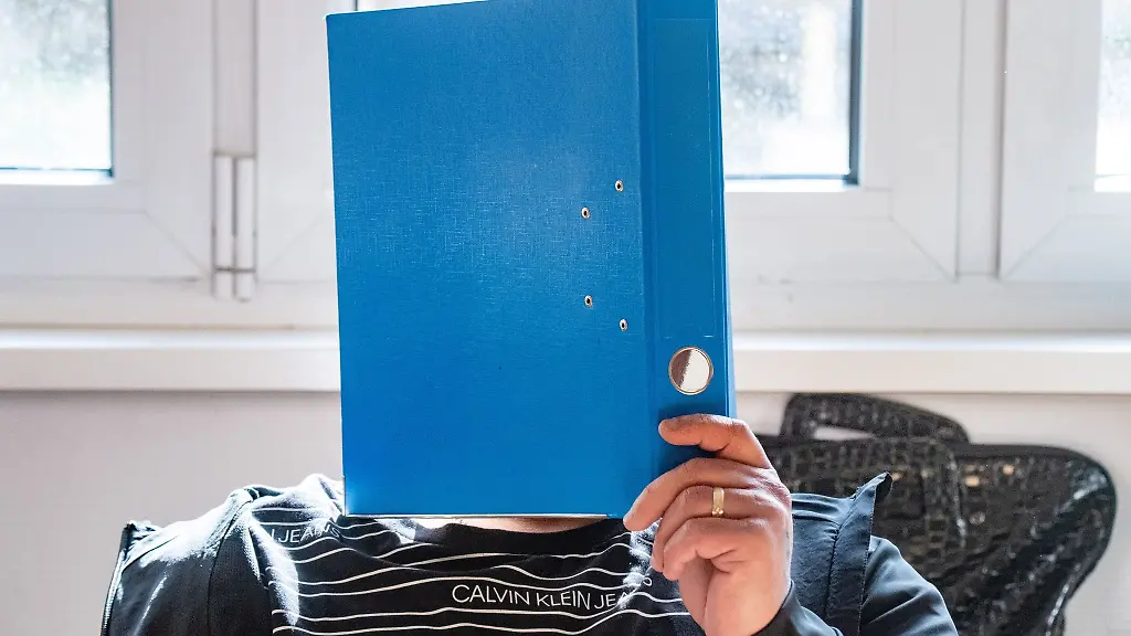 Der-Angeklagte-haelt-sich-im-Sitzungssaal-im-Landgericht-Stralsund-einen-Aktenordner-vor-das-Gesicht