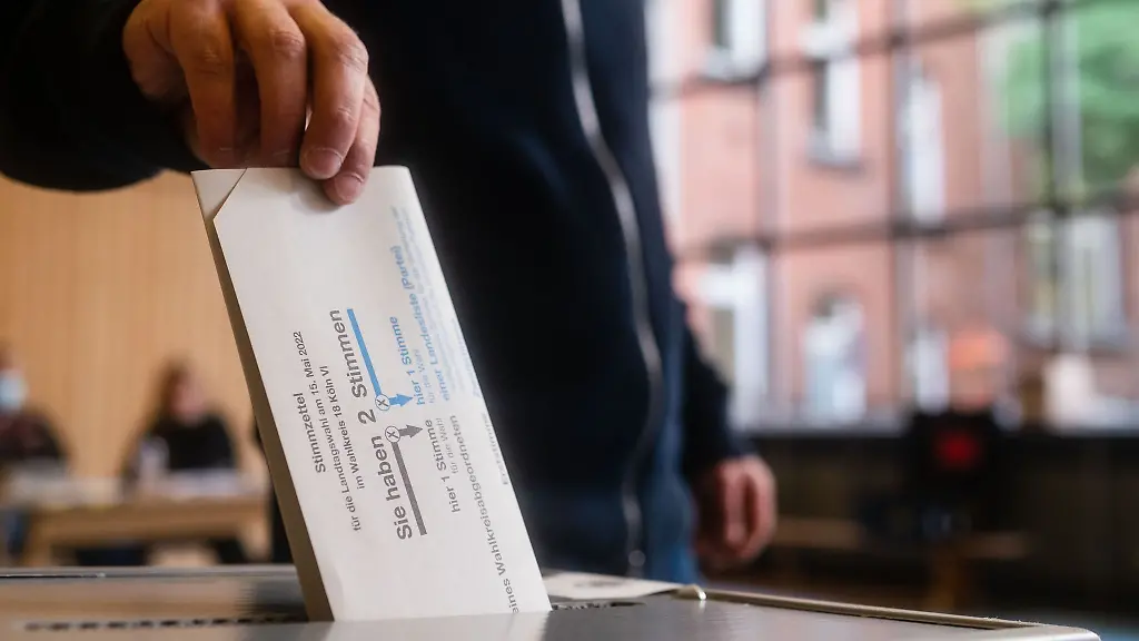 Ein-Mann-wirft-in-einer-Sporthalle-seinen-Stimmzettel-in-die-Wahlurne