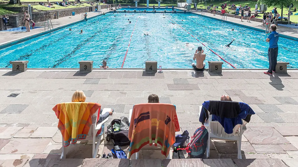 Badegaeste-sitzen-in-einem-Schwimmbad-in-Liegestuehlen