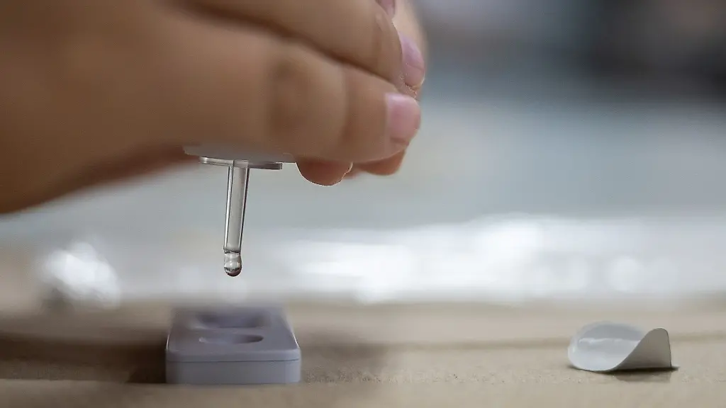 Eine-Person-tropft-eine-Fluessigkeit-in-einen-Corona-Schnelltest