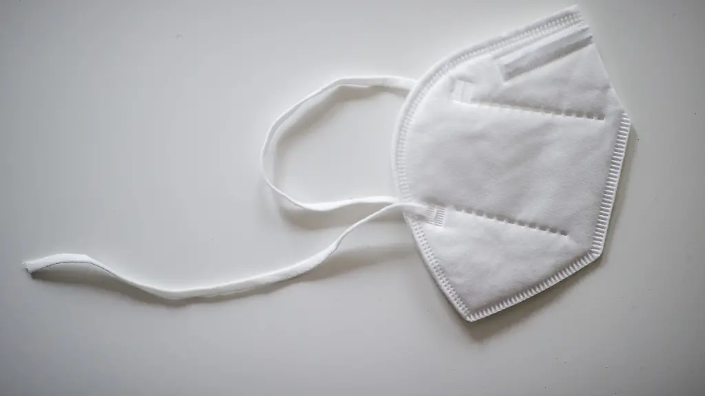 Eine-FFP2-Maske-mit-defektem-Gummiband-liegt-auf-einem-Tisch