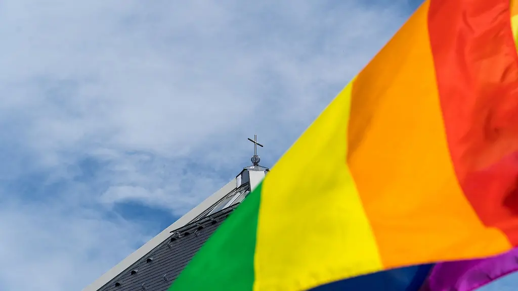 Eine-Regenbogenfahne-weht-vor-der-Kirche-St-Christophorus-am-Rande-der-Segnung-queerer-Menschen