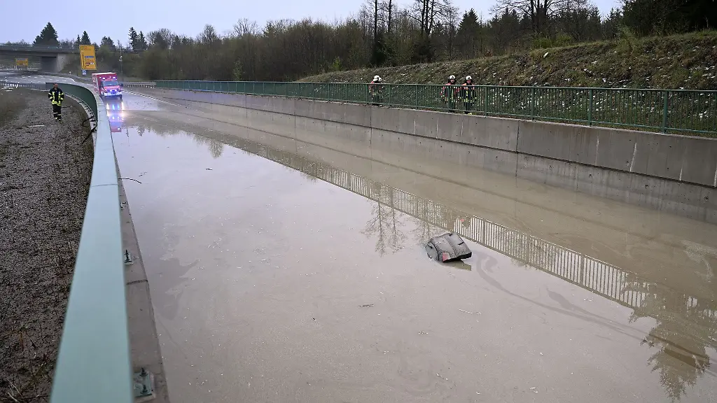 Die-Heckklappe-eines-Autos-ragt-aus-dem-Wasser-dass-teilweise-die-Bundesstrasse-B23-ueberflutet-hat