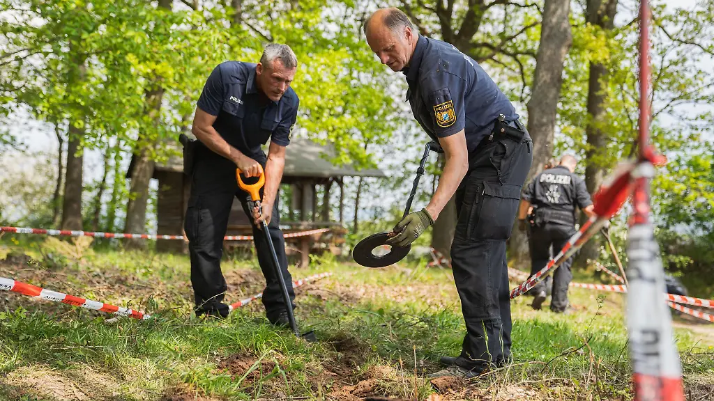 Polizisten-suchen-abgesteckte-Bereiche-rund-um-den-Fundort-des-Ermordeten-mit-Metalldetektoren-ab