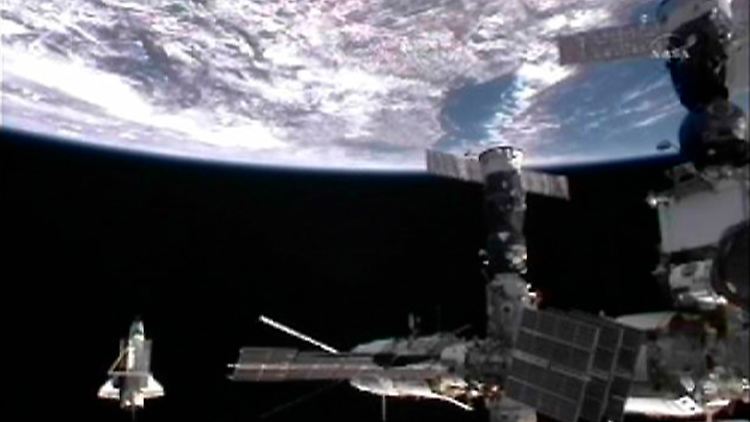Die "Discovery", links unten, umrundet ein letztes Mal die internationale Raumstation ISS.