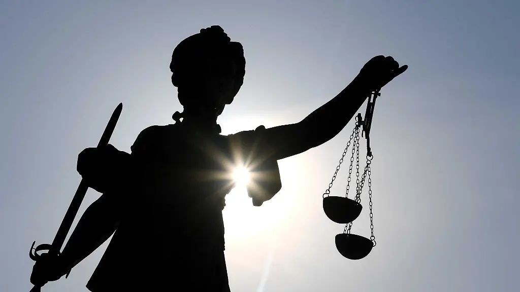 Eine-Statue-der-Justitia-steht-mit-Waage-und-Schwert-in-der-Hand
