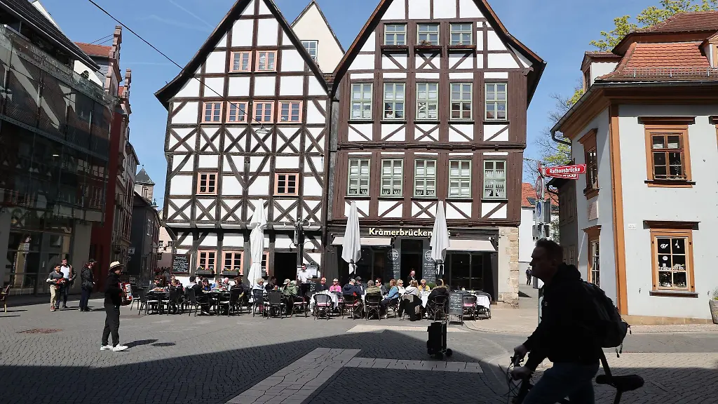 Zahlreiche-Gaeste-sitzen-vor-Restaurants-und-Cafes-im-Zentrum-der-Stadt