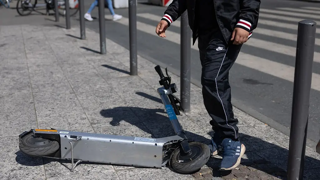 Ein-Passant-steigt-ueber-einen-abgelegten-E-Scooter-in-Frankfurt-am-Main