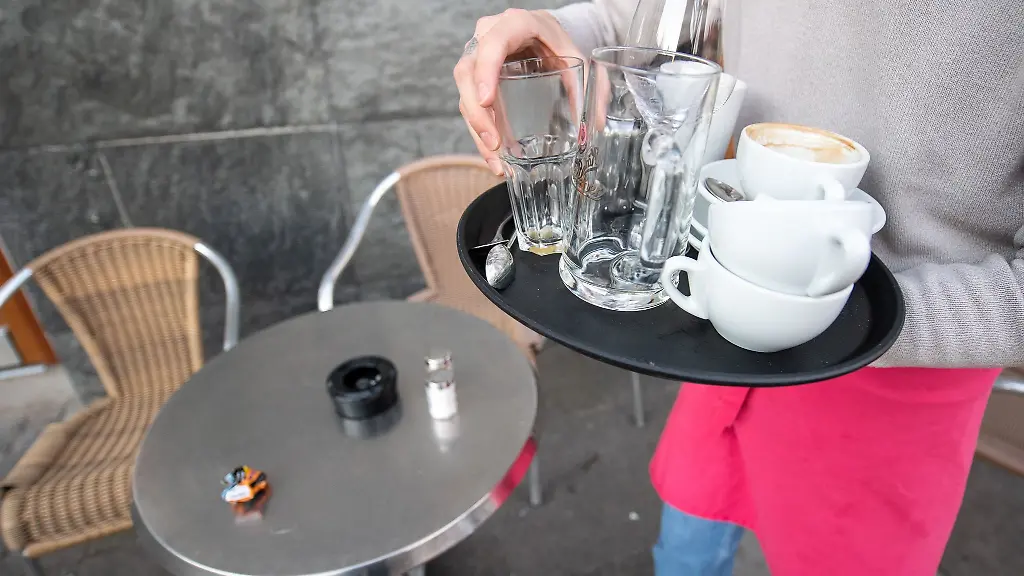 Eine-Servicekraft-raeumt-die-Tische-in-einem-Cafe-ab