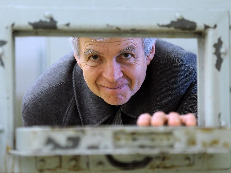 Der ehemalige Stasi-Häftling Gilbert Furian blickt durch die Türklappe einer Zelle in der Stasi-Gedenkstätte Berlin-Hohenschönhausen.