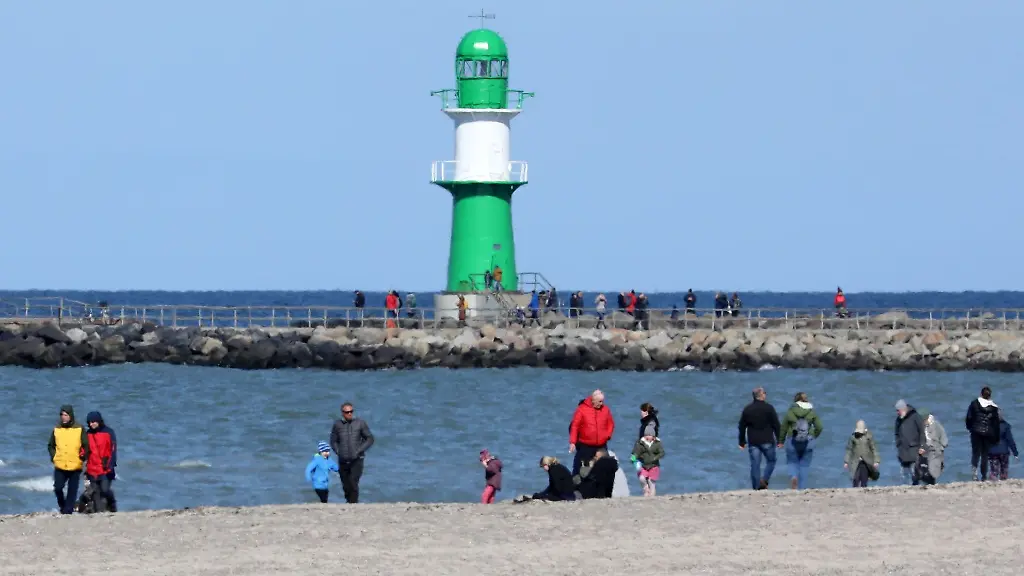Spaziergaenger-sind-bei-Sonnenschein-am-Ostseestrand-unterwegs