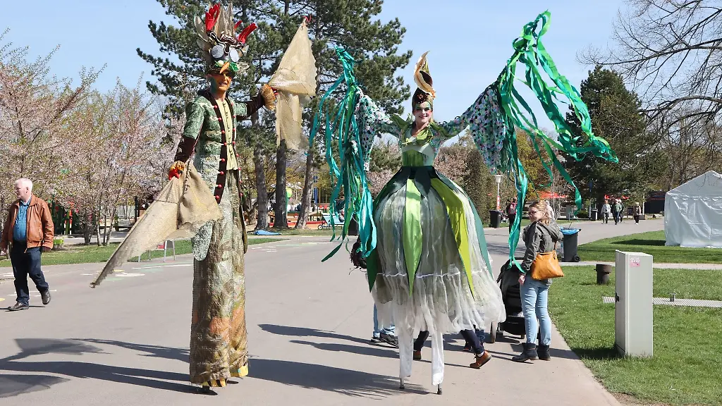 Als-Fruehlingsboten-verkleidete-Menschen-auf-Stelzen-laufen-auf-dem-Gelaende-der-Erfurter-Gartenschau-EGA