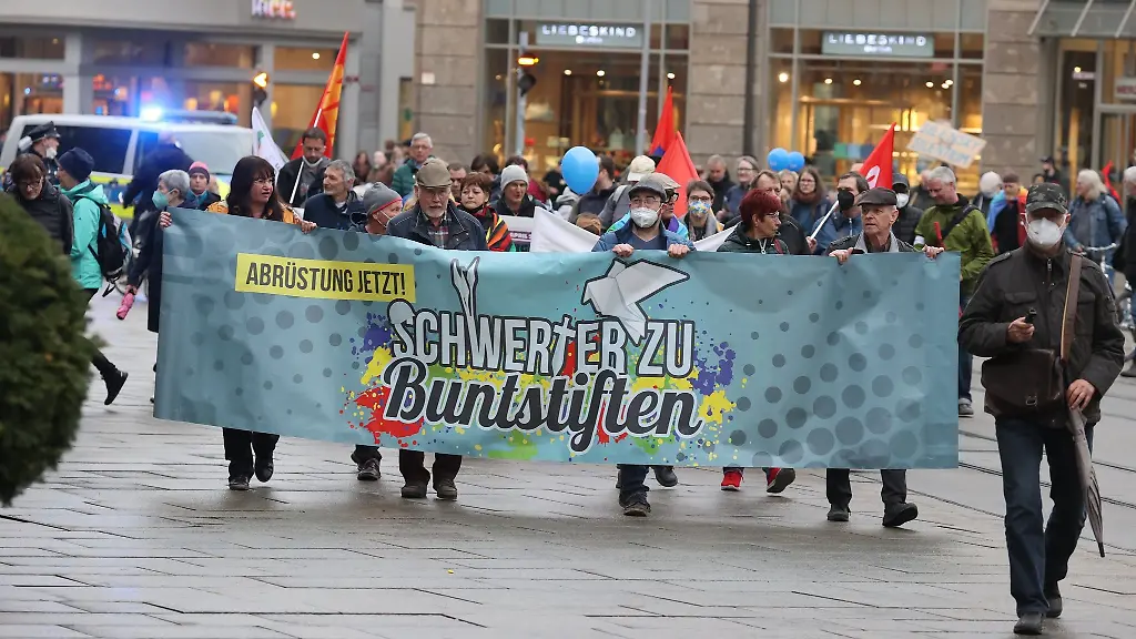 Teilnehmer-eines-Ostermarsches-laufen-mit-Plakaten-auf-dem-Anger