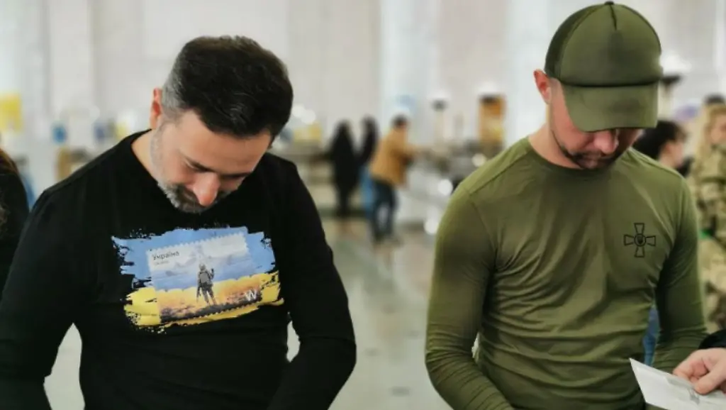 Der-ukrainische-Soldat-Roman-Hrybow-rechts-und-Postchef-Ihor-Smyljanskyj-signieren-im-Hauptpostamt-die-neuen-speziellen-Briefmarken