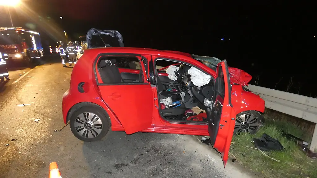 Ein-stark-beschaedigter-Kleinwagen-steht-an-einer-Leitplanke