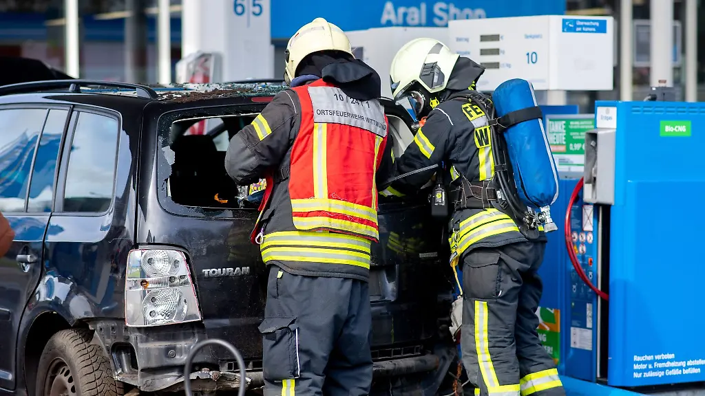 Einsatzkraefte-der-Feuerwehr-untersuchen-an-einer-Tankstelle-ein-Erdgasfahrzeug