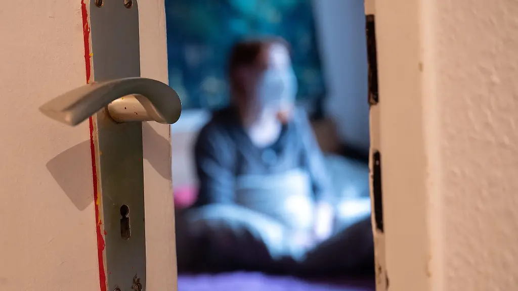 Eine-Frau-sitzt-waehrend-der-Isolation-nach-einem-positiven-Corona-PCR-Test-auf-ihrem-Bett