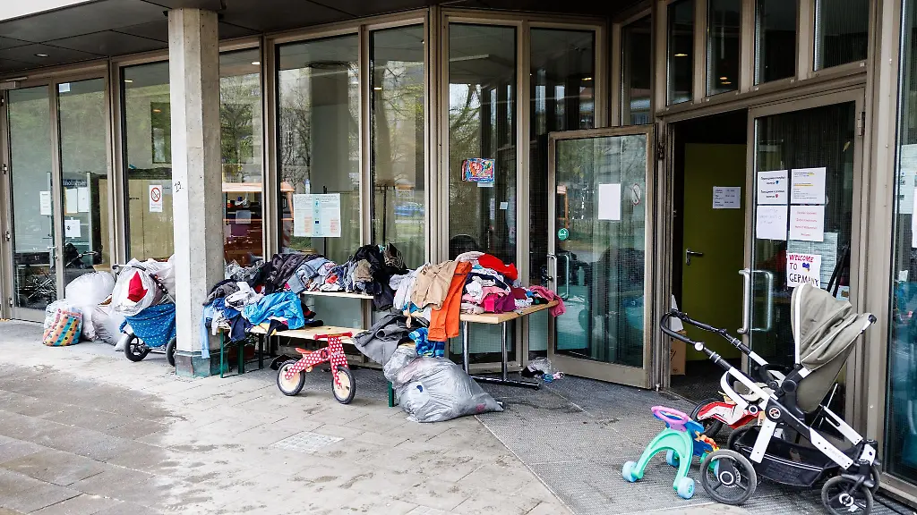 Ein-Laufrad-und-zahlreiche-Kleidungsstuecke-sind-vor-einer-Fluechtlings-Notunterkunft-zu-sehen