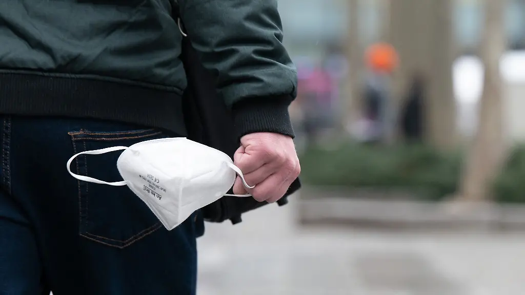 Ein-Mann-haelt-eine-FFP2-Maske-in-der-Hand