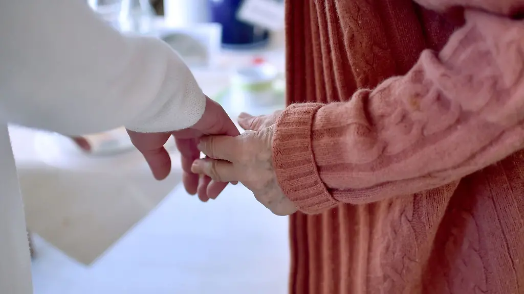 Eine-Pflegekraft-haelt-die-Hand-einer-Bewohnerin-einer-Pflegeeinrichtung