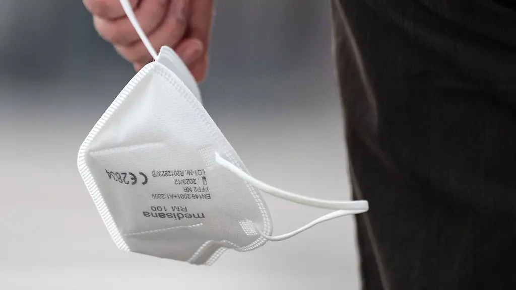 Ein-Passant-traegt-eine-FFP2-Maske-in-der-Hand