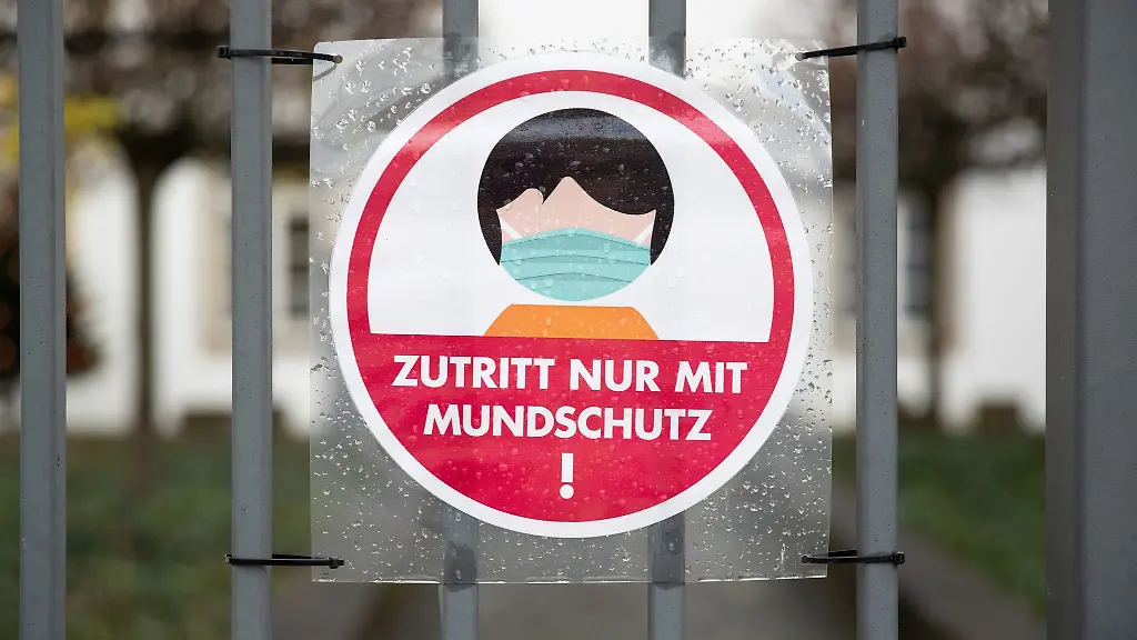 Ein-Schild-an-einem-Eingang-weist-auf-das-Tragen-einer-Maske-hin