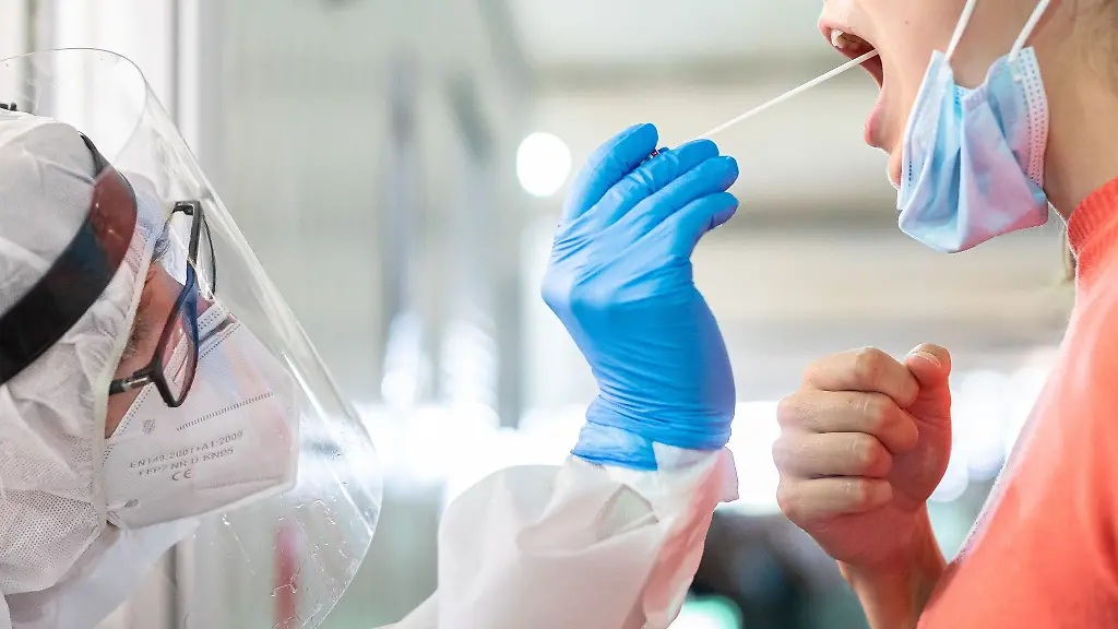 Ein-medizinischer-Mitarbeiter-entnimmt-einer-Frau-einen-Abstrich-fuer-einen-Corona-Test