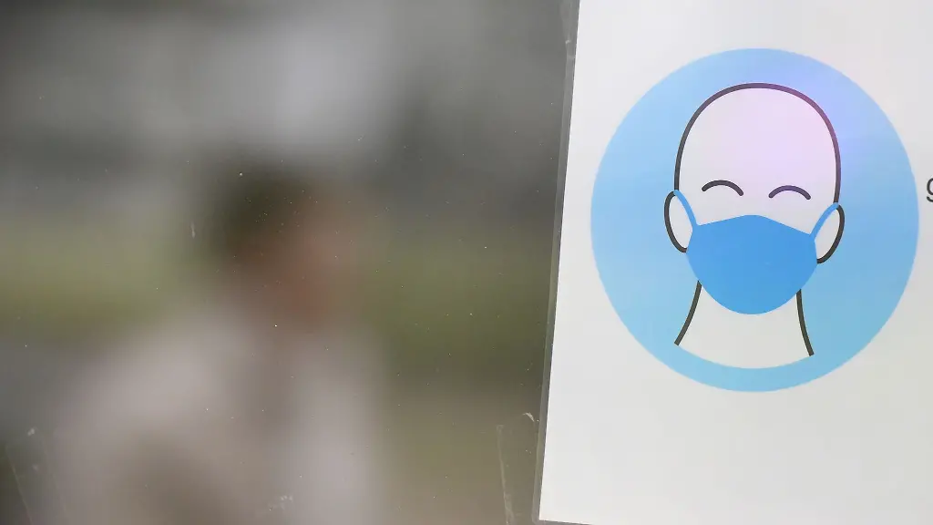 Ein-Hinweisschild-zum-Tragen-von-Schutzmasken-haengt-an-einer-Tuer