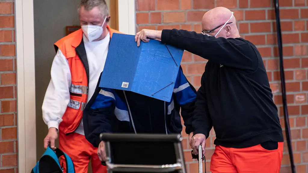 Der-angeklagte-ehemaligen-KZ-Wachmann-kommt-mit-Hilfe-von-Sanitaetern-zur-Fortsetzung-des-Prozesses-in-den-Gerichtssaal-in-einer-Turnhalle