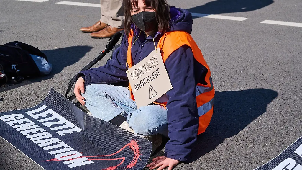 Klimaaktivisten-der-Initiative-Letzte-Generation-sitzen-teilweisse-mit-festgeklebten-Haenden-auf-der-Ebertstrasse-vor-dem-Brandenburger-Tor-und-demonstrieren