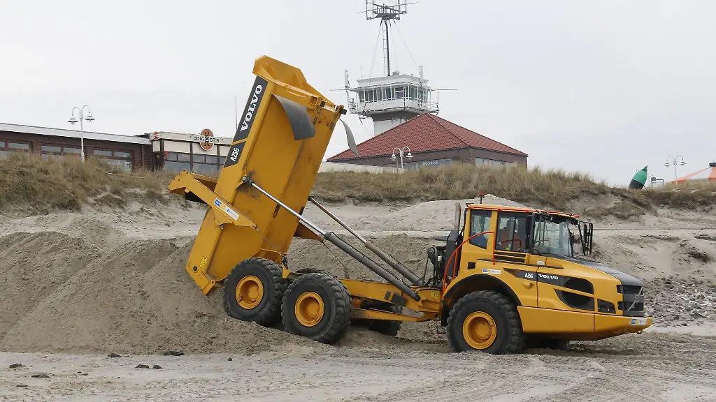 Ein-Muldenkipper-schuettet-am-Badestrand-von-Wangerooge-Sand-auf