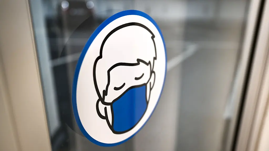 Ein-Aufkleber-an-einer-Glastuer-weist-auf-das-Tragen-einer-Maske-hin