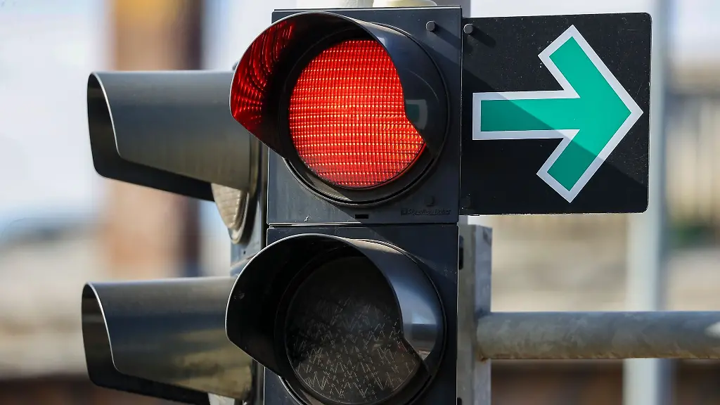 Ein-Gruener-Pfeil-haengt-neben-einer-roten-Ampel-an-einer-Kreuzung-und-erlaubt-das-Abbiegen-trotz-Rotlicht