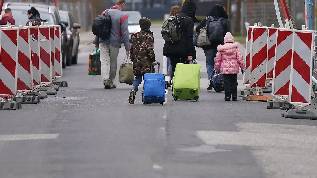 Ukrainische-Fluechtlinge-laufen-mit-ihrem-Gepaeck-ueber-eine-Strasse