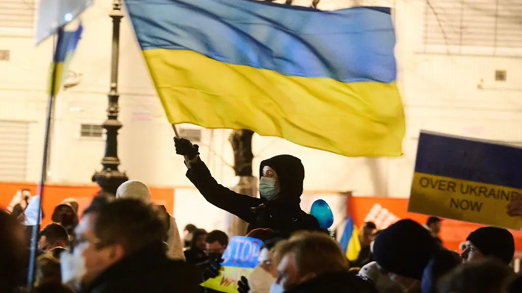 Ein-Teilnehmer-schwingt-eine-ukrainische-Fahne-waehrend-einer-Mahnwache-vor-der-Russischen-Botschaft