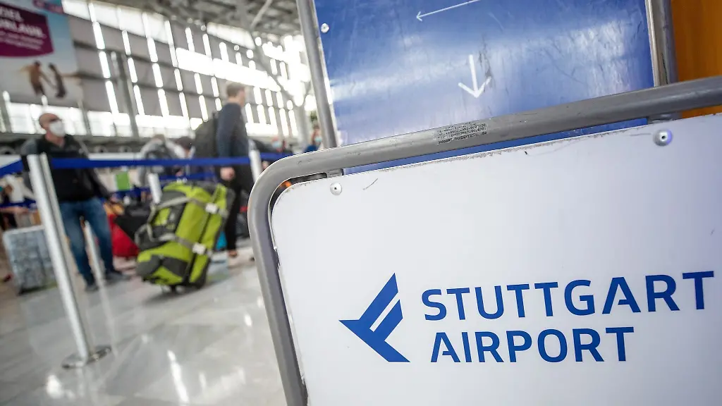Fluggaeste-gehen-mit-ihrem-Gepaeck-zu-Check-In-Schaltern-am-Flughafen-Stuttgart