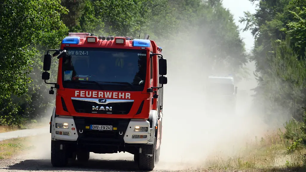 Ein-Fahrzeug-der-Feuerwehr-faehrt-auf-dem-sandigen-Weg-durch-den-Wald