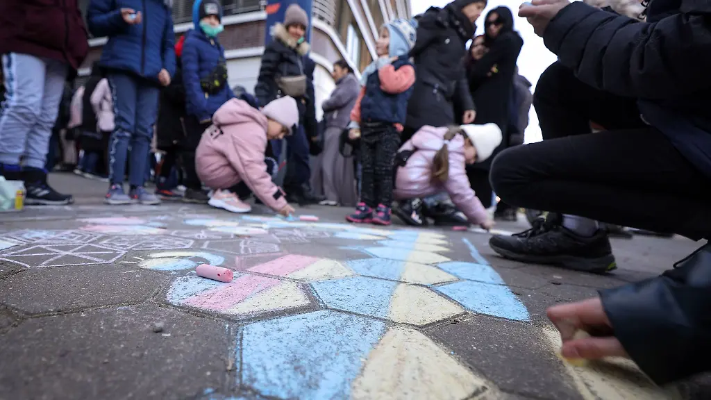 Kinder-die-mit-ihren-Angehoerigen-nach-deutschland-geflohen-sind-malen-mit-Kreide-auf-den-Boden