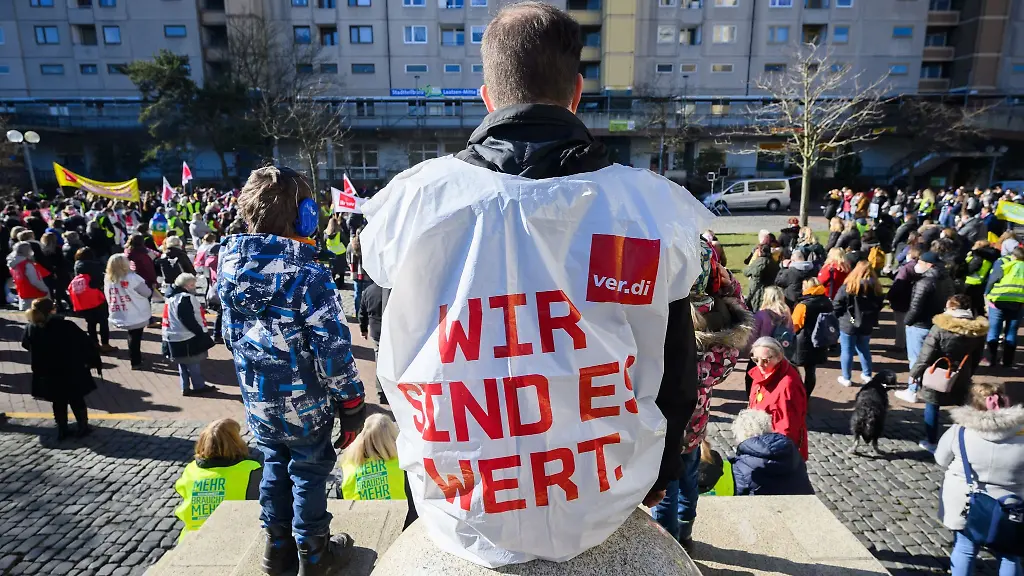 Ein-Erzieher-einer-Kindertagesstaette-sitzt-mit-einer-Verdi-Weste-bei-einem-Warnstreik