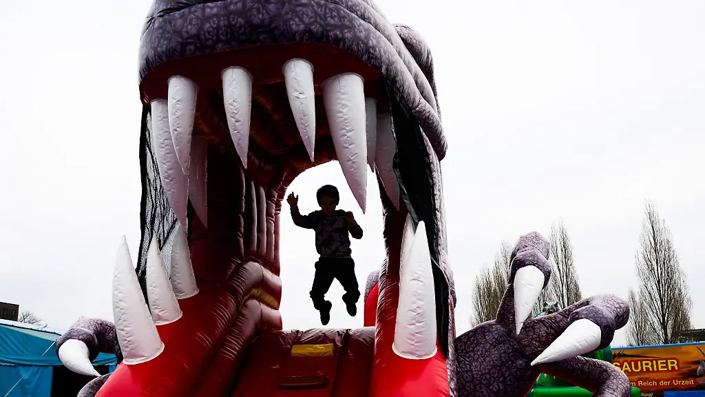 Ein-Kind-springt-in-einer-Huepfburg-in-Form-eines-Dinosauriers