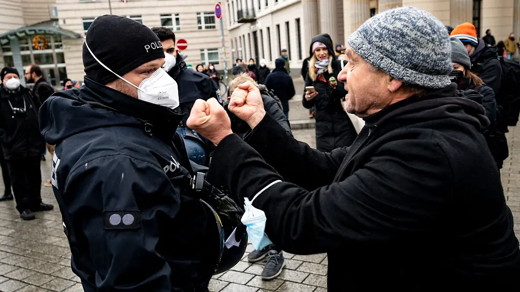 Ein-Teilnehmer-einer-Demonstration-gegen-Corona-Massnahmen-streckt-einem-Polizisten-seine-Faeuste-entgegen