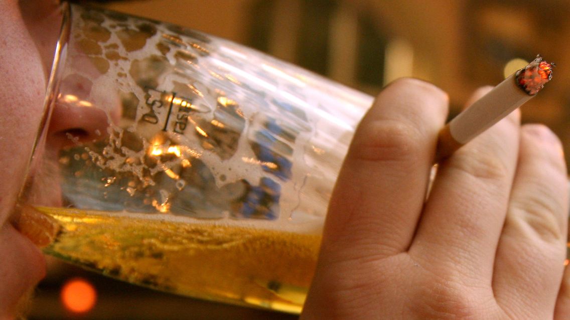 Ein Mann trinkt in einer Gaststätte Bier und raucht dazu eine Zigarette - in Basel