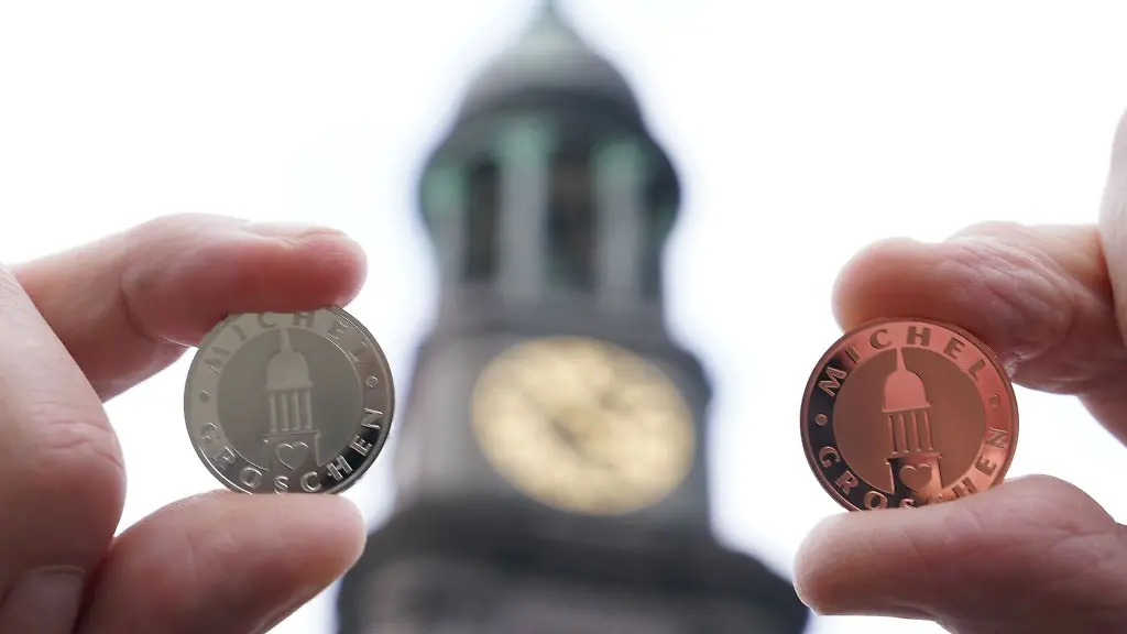 Ein-silberner-und-ein-kupferner-Michel-Groschen-werden-vor-dem-Hamburger-Michel-hochgehalten