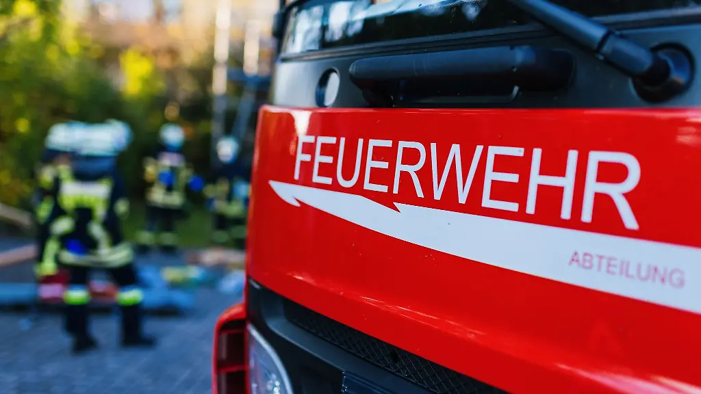 Feuerwehrleute-stehen-hinter-einem-Einsatzfahrzeug