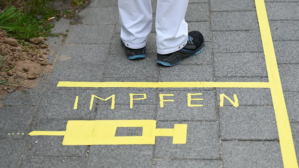 Ein-Mann-steht-an-einem-Covid-19-Impfcenter-hinter-der-Bodenaufschrift-Impfen