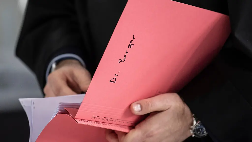 Ein-Rechtsanwalt-des-Hauptbeschuldigten-Hanno-Berger-haelt-vor-dem-Prozessauftakt-um-Cum-Ex-Aktiendeals-im-Gerichtssaal-eine-Akte-mit-der-Aufschrift-Dr-Berger-in-der-Hand