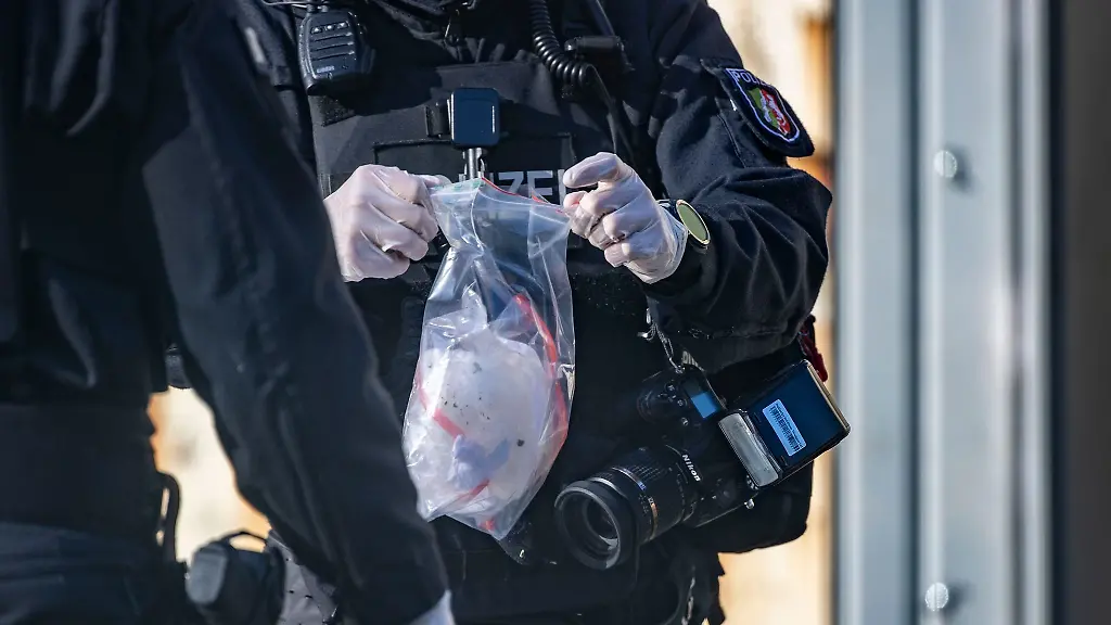 Ein-Polizist-haelt-eine-Tuete-in-der-Hand-die-vorher-aus-einem-Hohlraum-geholt-wurde