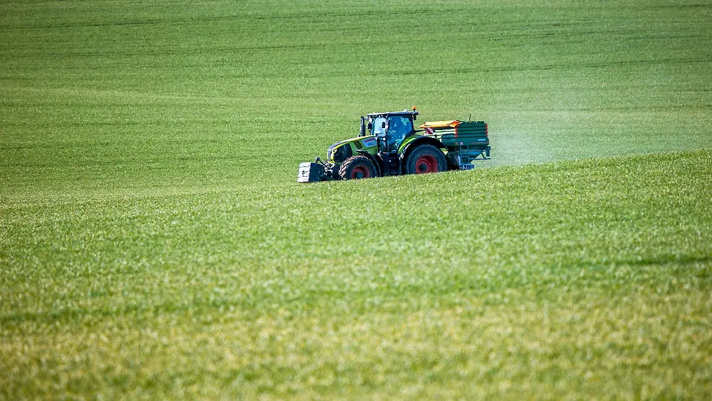 Ein-Traktor-mit-einem-Streuaufsatz-verteilt-Duenger-auf-einem-Feld