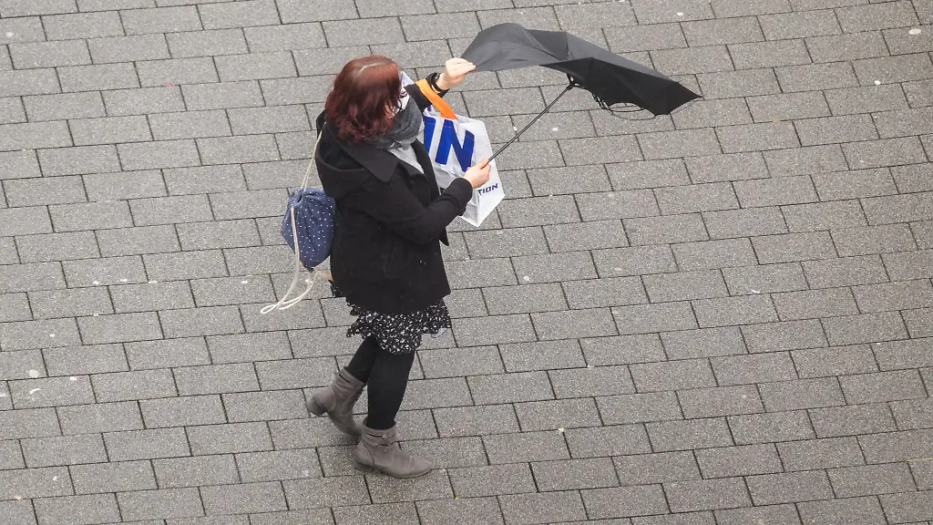 Der-Regenschirm-einer-Frau-wird-von-einer-Windboee-erfasst